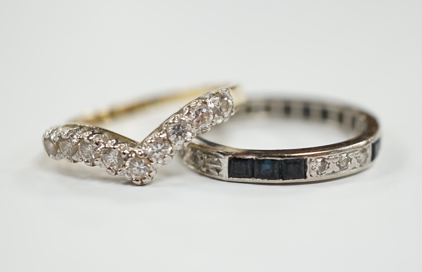 A white metal sapphire and diamond set full eternity ring, size Q/R, gross weight 3.6 grams, together with a 14k and cubic zirconia set chevron ring, gross 2.8 grams. Condition - fair to poor